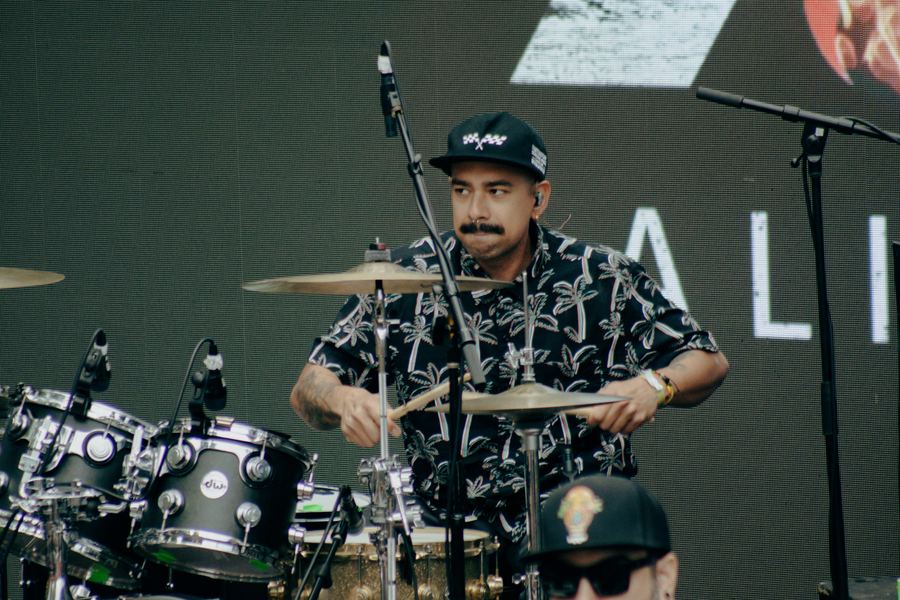 Drummer driving a live set, kit and stage behind him