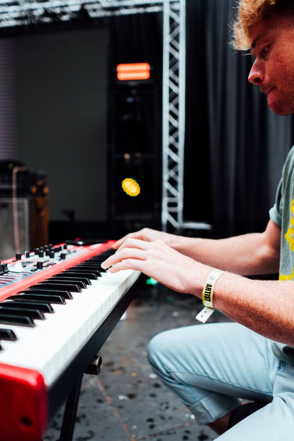 Hands playing a red keyboard during a live set