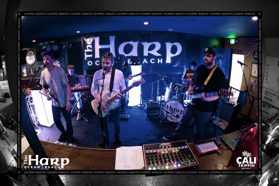Band playing on a club stage beneath a lit venue sign