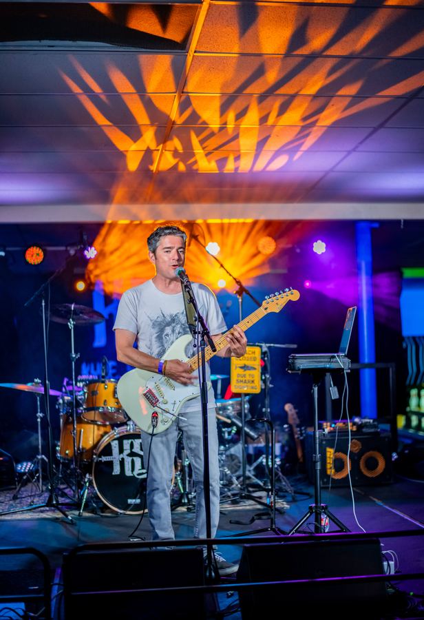 Musician singing and playing guitar on a lit stage