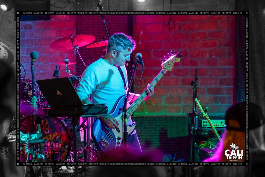 Band playing a small stage washed in red and magenta light