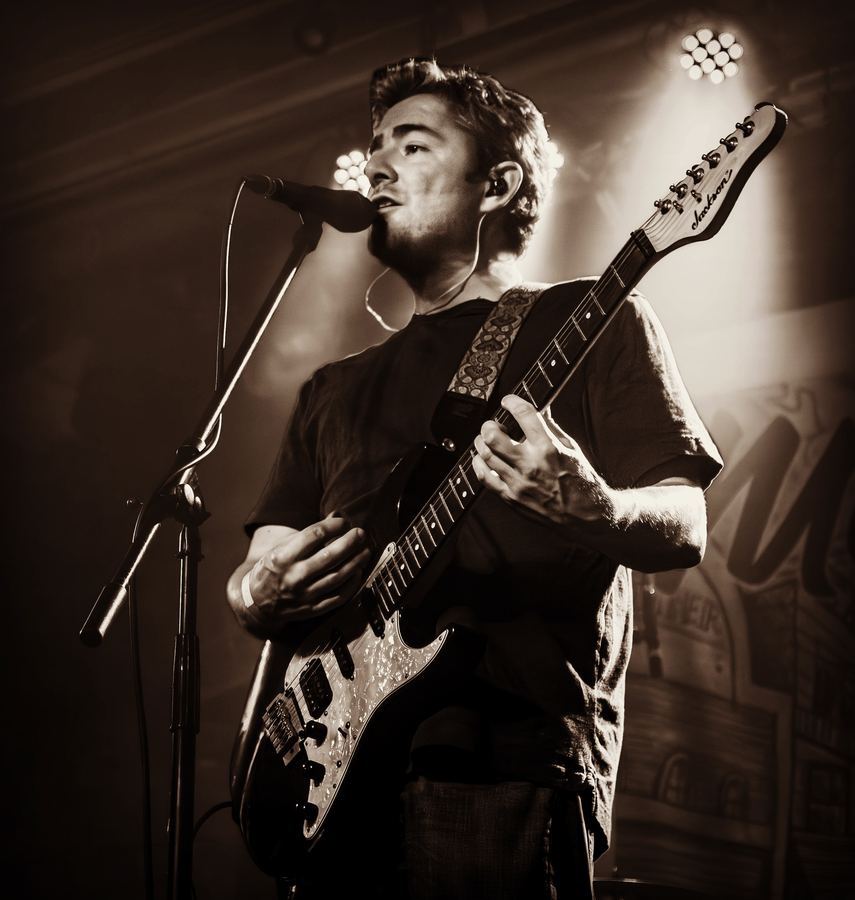 Musician singing into a microphone while playing guitar