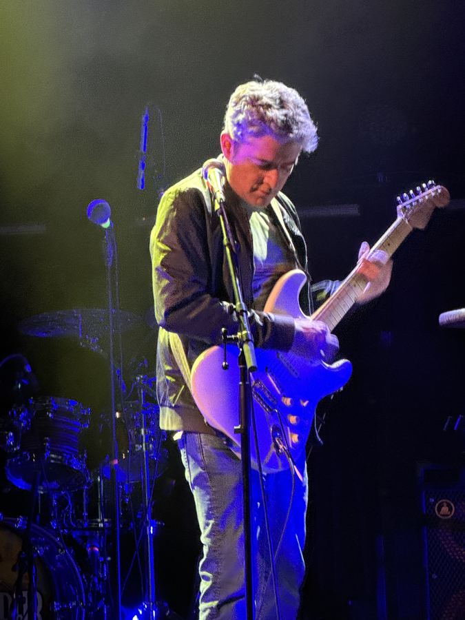 Guitarist singing on a purple-lit stage