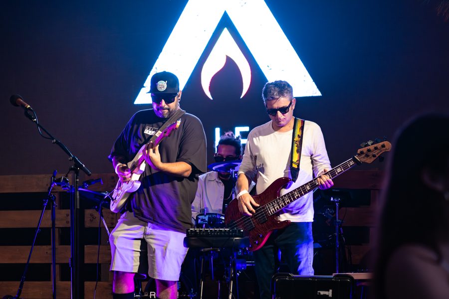 The full band on stage in front of the lit Alific backdrop