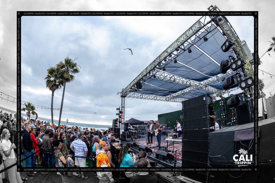 Stage rig and palms with the crowd gathering at an outdoor show