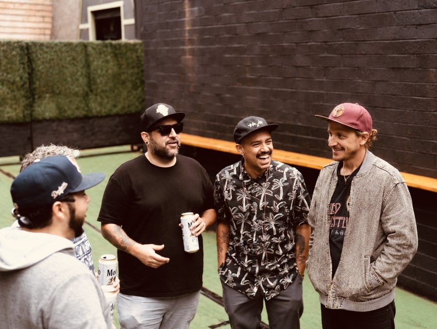 Band members gathered together in front of a green wall