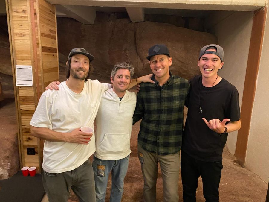 Alific and three friends posing together inside a cave with rock walls